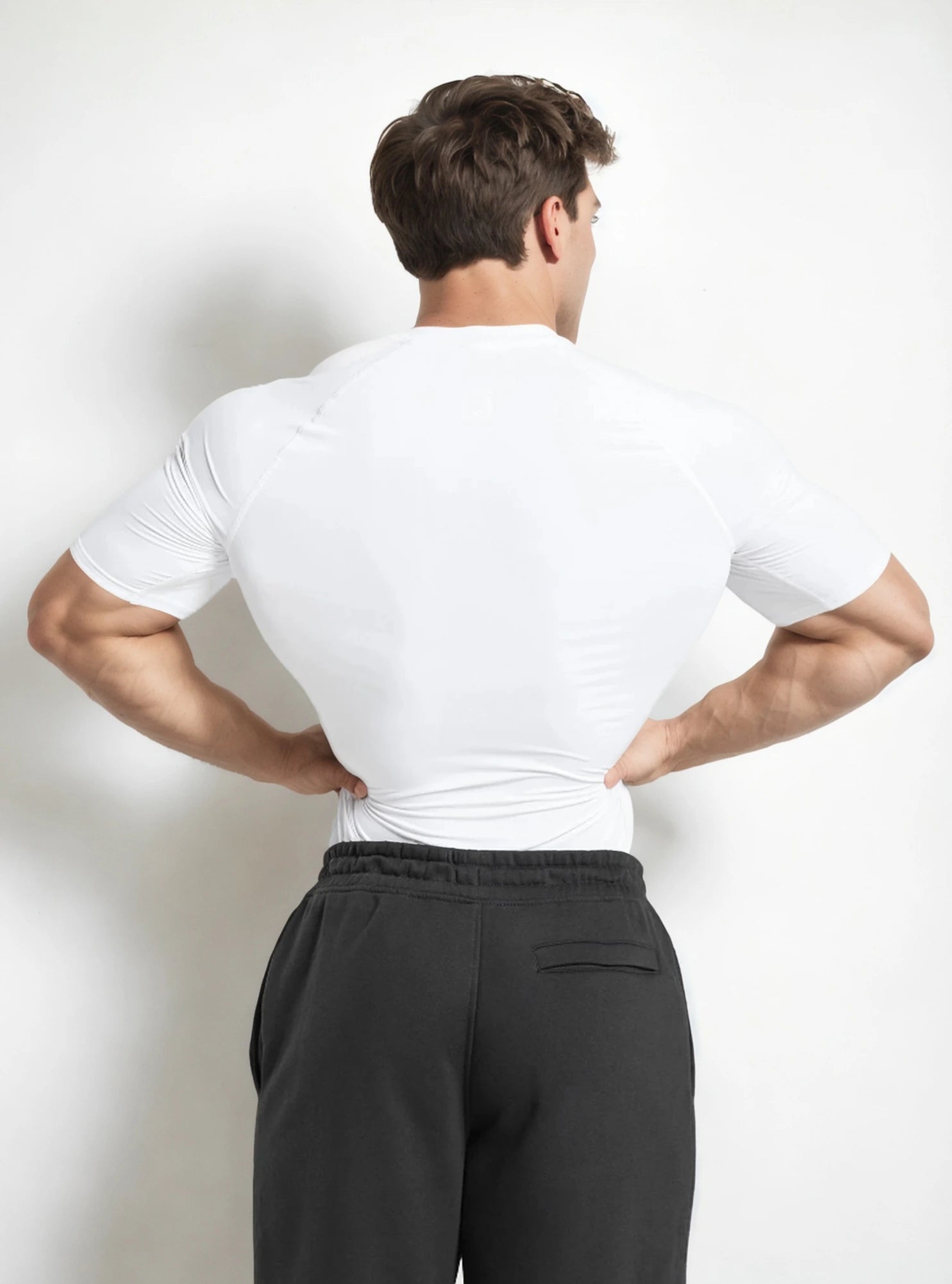 Back image of a fitness male model wearing white colour radowl half sleeve gym compressor tshirt standing whitedrop background.